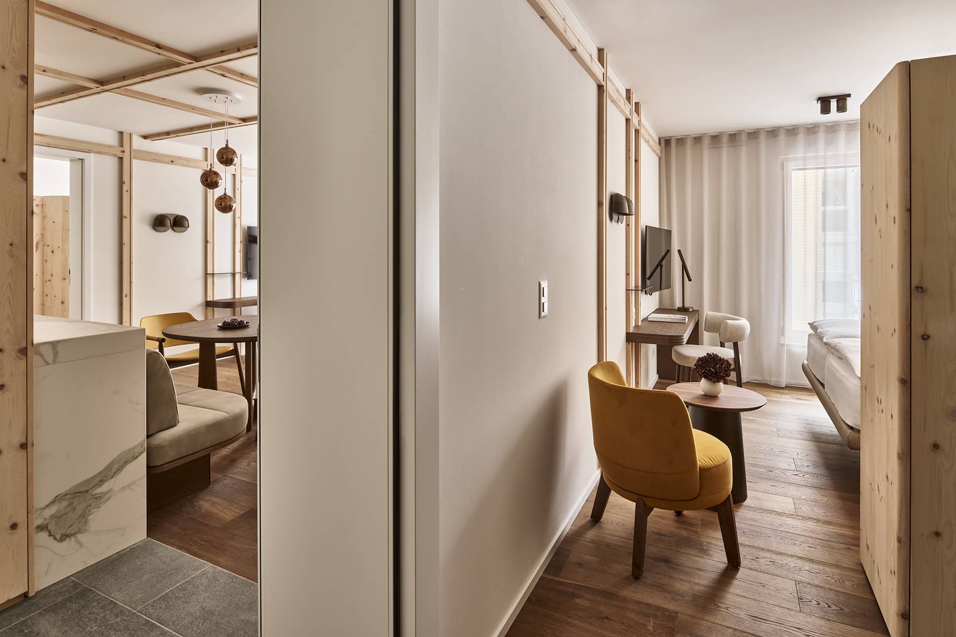 Blick vom Flur in den Schlafbereich mit Doppelbett, Holzelementen und natürlichem Tageslicht