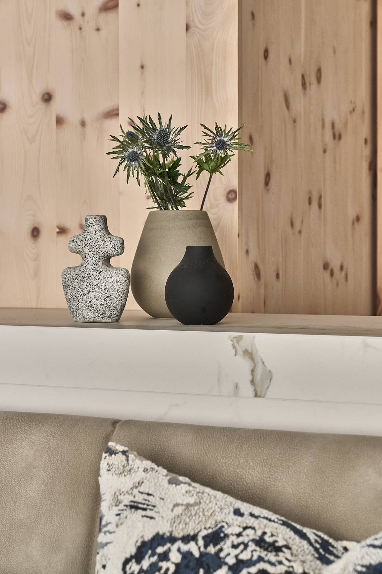 Dekorative Details auf der Küchenablage mit modernen Vasen und floralen Akzenten vor Holzverkleidung.