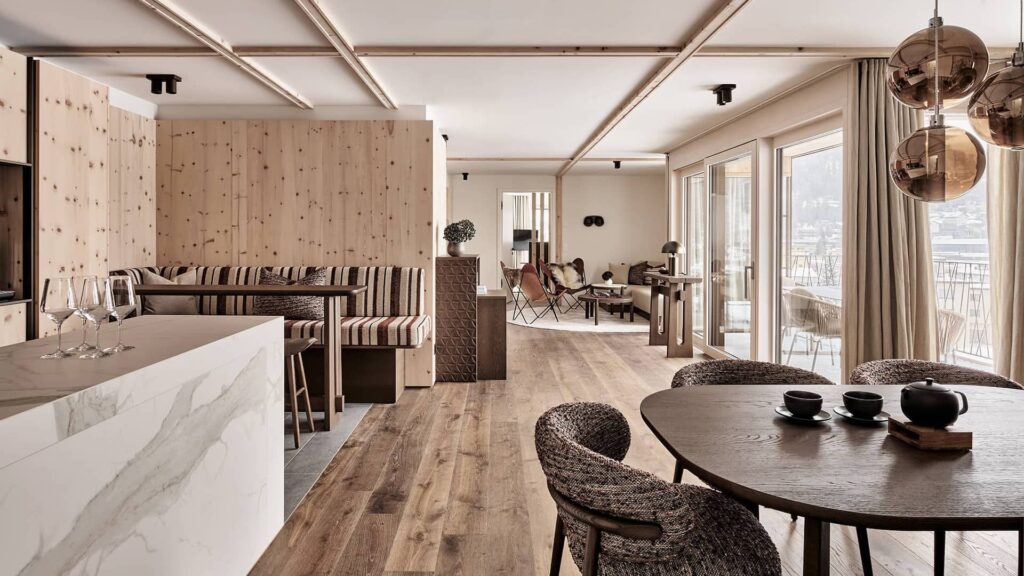 Offener Wohn- und Essbereich des Penthouses mit Küche, Sitzbank und Blick durch bodentiefe Fenster