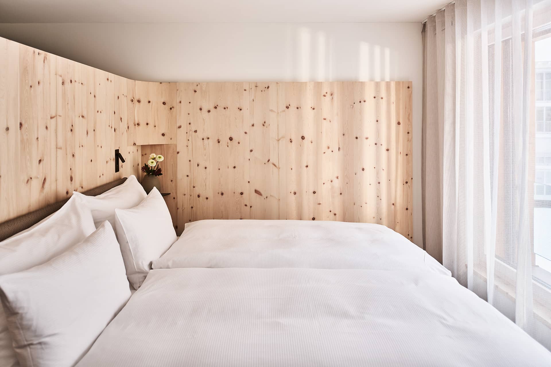 Schlafzimmer im Loft mit Doppelbett, Holzwand und Tageslicht