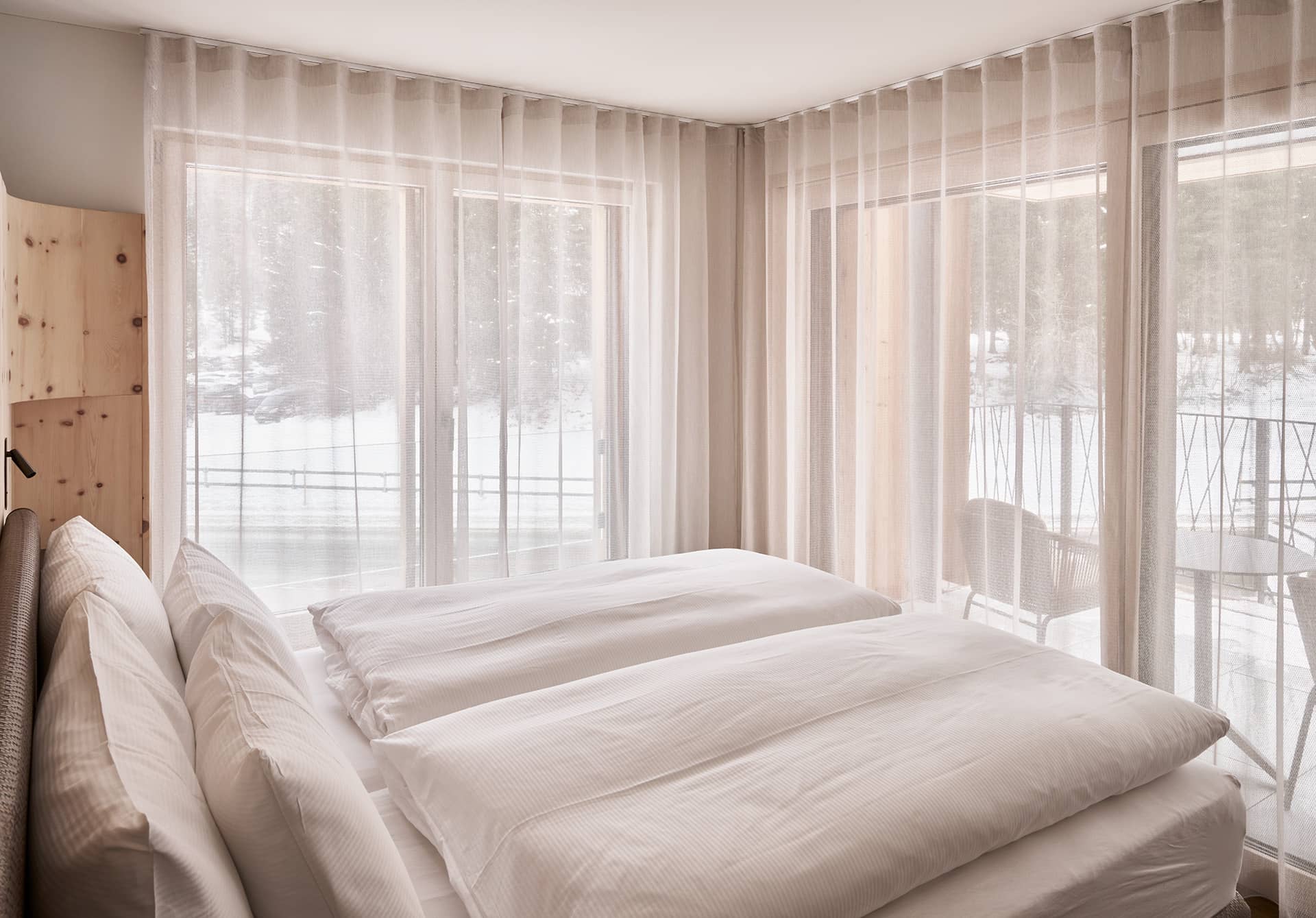 Schlafzimmer der Suite 2 mit Doppelbett, Balkonzugang und Blick ins Winterpanorama