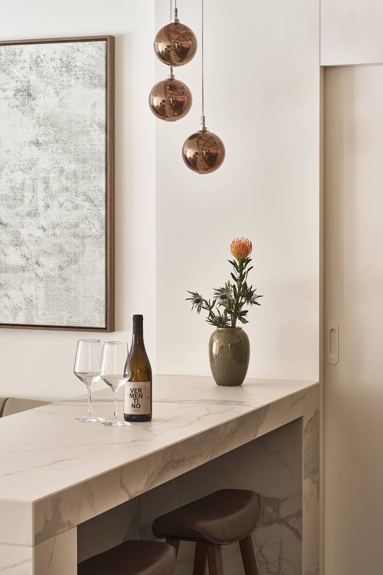 Detail der Kücheninsel in der Suite 2 mit Natursteinoberfläche, Barhockern und Pendelleuchten