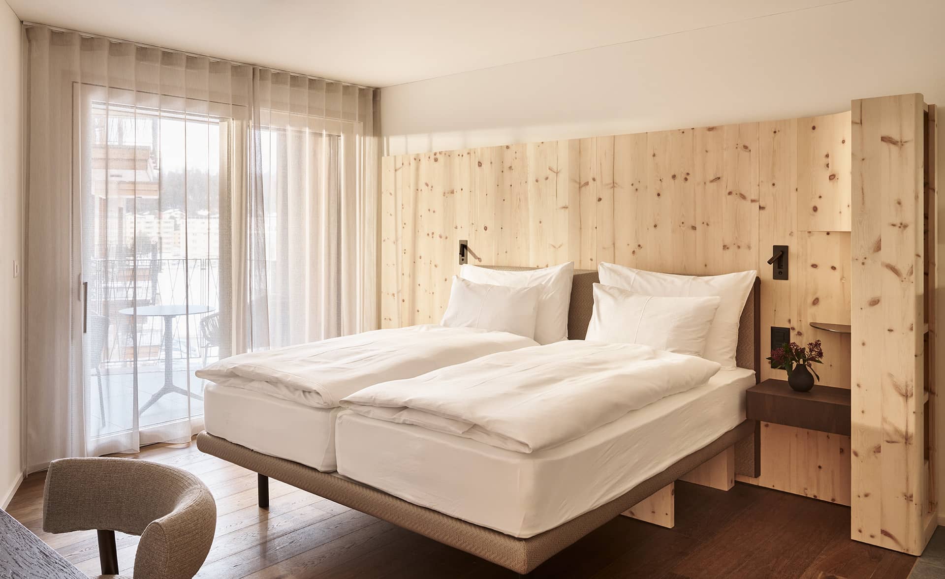 Schlafbereich der Suite mit Doppelbett, Holzrückwand und Balkonzugang