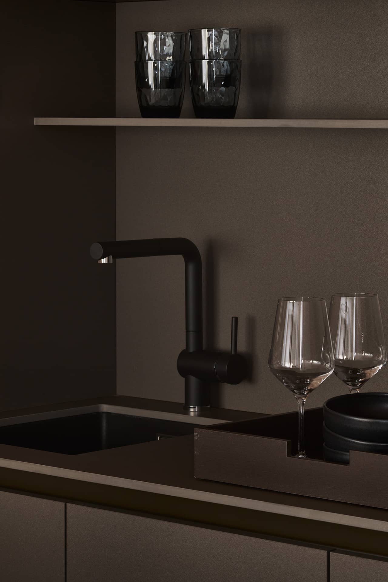 Moderne Kitchenette im Studio mit dunkler Armatur, Weingläsern und minimalistischem Küchendesign.