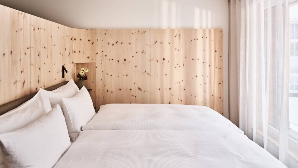 Helles Studio mit gemütlichem Wohn- und Schlafbereich, Holzwänden, Doppelbett und großer Fensterfront mit viel Tageslicht