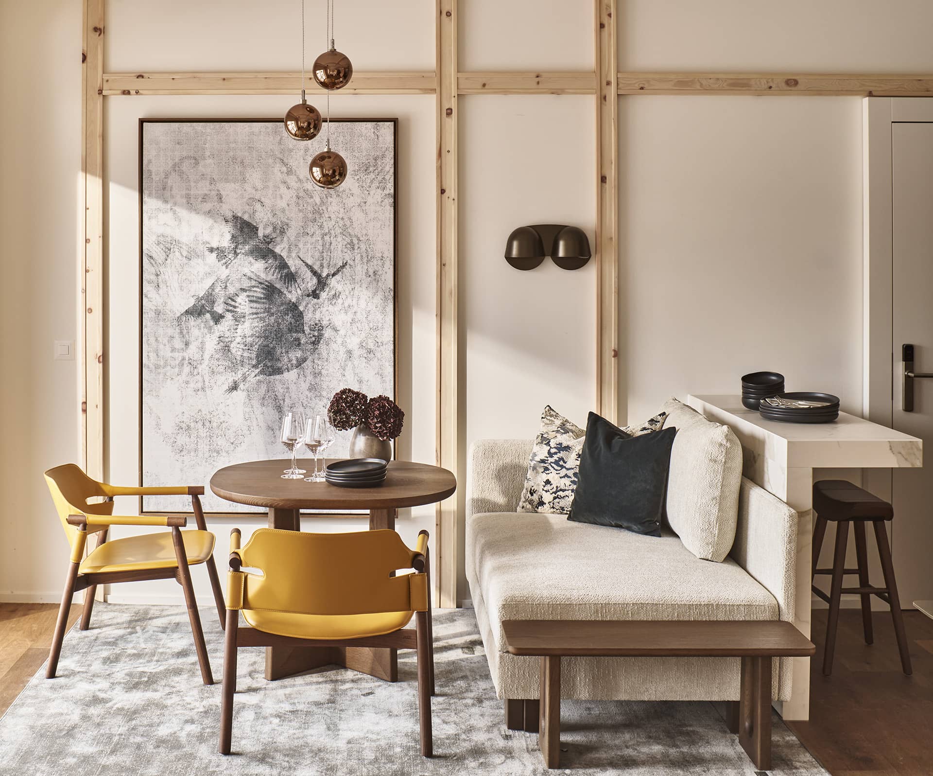 Gemütlicher Wohn- und Essbereich im Loft mit Sofa, rundem Holztisch und moderner Holzstruktur an der Wand.